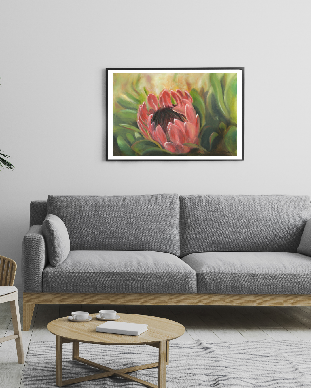Limited edition print of ‘Protea Majesty’ displayed above a grey couch. The bold protea artwork by Stephreen Mapstone adds a vibrant focal point, bringing warmth and contrast to the neutral-toned living space.
