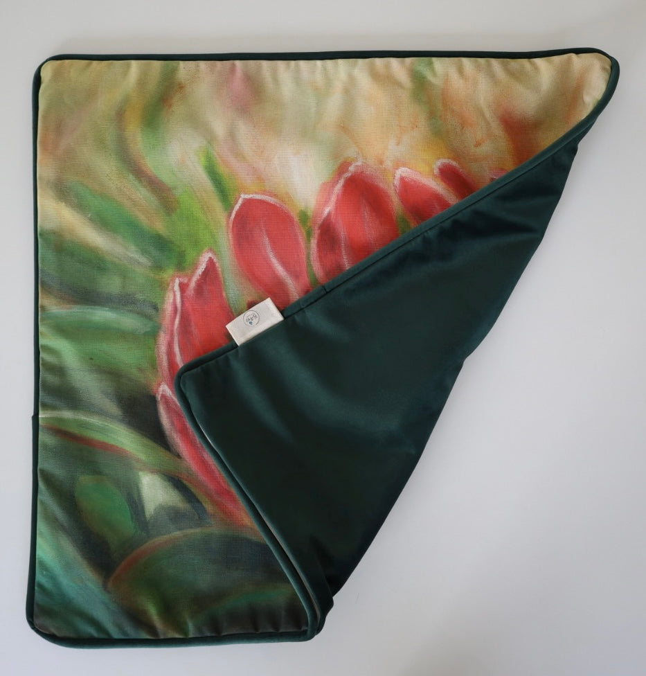 Image shows folded back and front of square 60×60 cm cushion cover with pink  protea with green leaves from oil painting print, velvet piping, velvet back, and concealed zip closure.