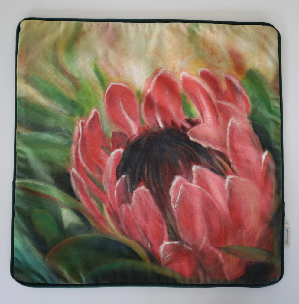 Image shows front of square 60×60 cm cushion cover with pink  protea with green leaves from oil painting print, velvet piping, velvet back, and concealed zip closure.
